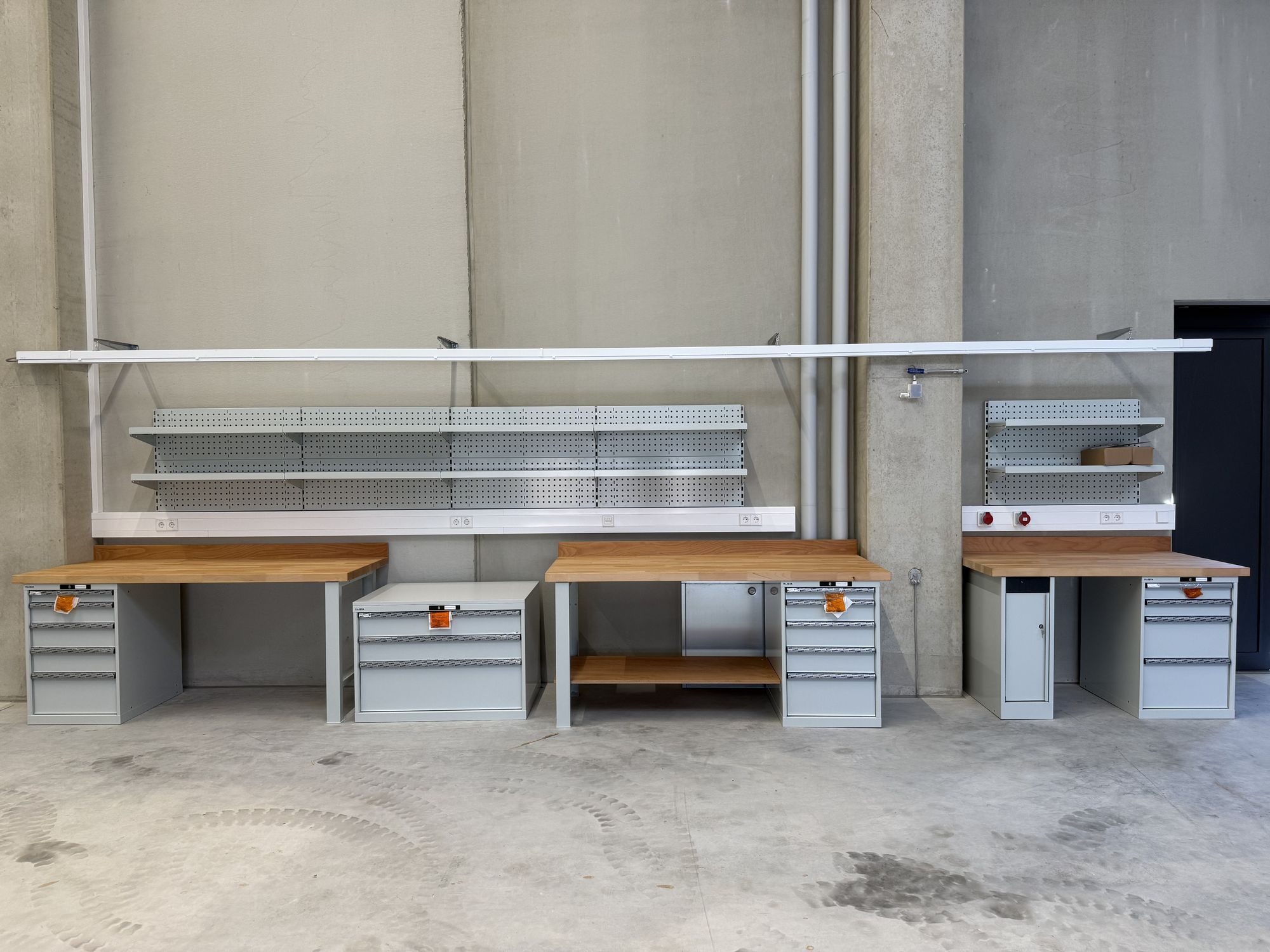 Neu montierte Werkbänke mit Schubladenschränken und Lochwänden in einer hellen Industriehalle
